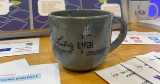 LIfBi-Tasse und Informationsmaterial auf einem Messestand der Fachmesse für digitale Verwaltung im Energiepark in Hirschaid.